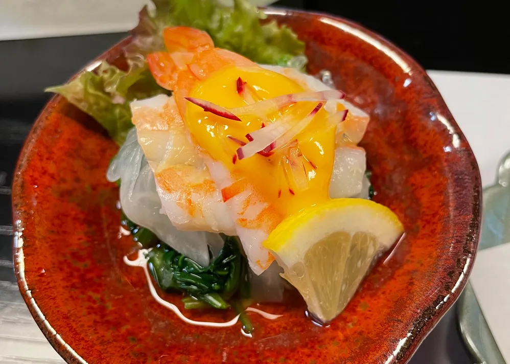 赤い小鉢に盛られたエビと黄身ソースの小鉢料理