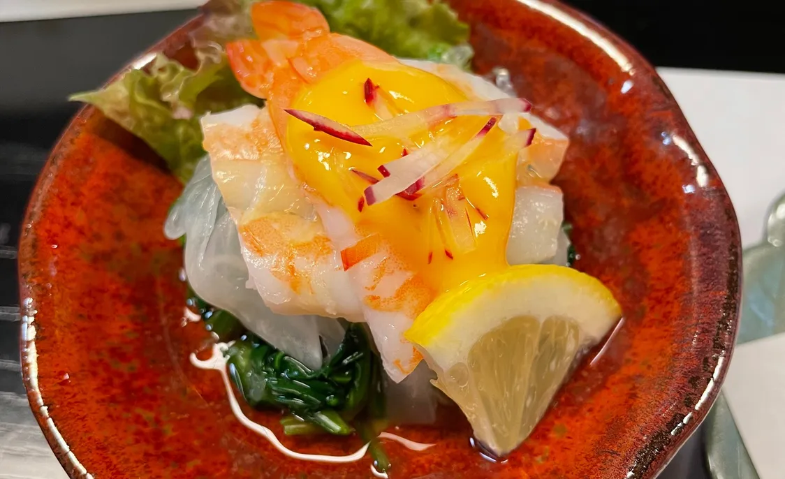 赤い小鉢に盛られたエビと黄身ソースの小鉢料理